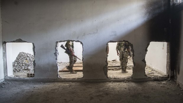 Members of the US-backed Syrian Democratic Forces (SDF) walk inside the stadium that was the site of Islamic State fighters' last stand in the city of Raqqa in October. 