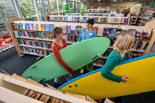 Fresh off the shelves: Locals Jo O’Reilly Stubbs (left) and Hanna Lofgren check out surfboards at Inverloch library, with staff member Sarah Cantwell looking on.