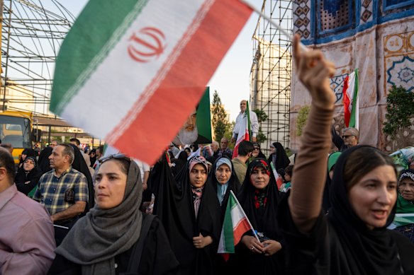 Protesters chant slogans and wave Iranian flags in Tehran’s Revolution Square to protest US attacks.