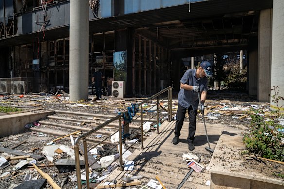 A man sweeps in front of the entrance of a building used by the Iranian Broadcasting Organisation, hit by an Israeli missile.