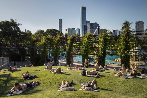 People sun themselves at South Bank in Brisbane, where the temperature hit a balmy 27.6 degrees on Monday.