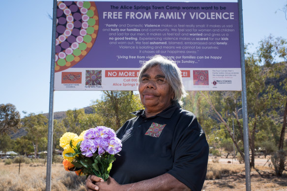 Helen Gillen and a family violence sign outside the Alice Springs town camps. 