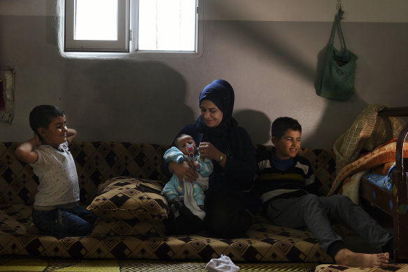 Syrian refugees Manal Hussein (second from right) holding two-month-old Omar Jalal. Ahmed, 12, is far right, in their brick shelter at Darashakran camp, Iraqi Kurdistan.