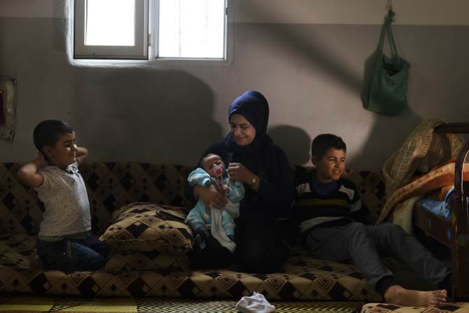 Syrian refugees Manal Hussein (second from right) holding two-month-old Omar Jalal. Ahmed, 12, is far right, in their brick shelter at Darashakran camp, Iraqi Kurdistan.