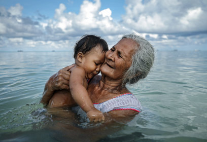 Suega Apelu bathes a child in Tuvalu, which is facing the disproportionate impacts of climate change.