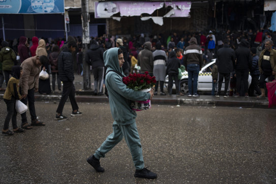 A Palestinian youth carries a bucket with roses at the market in Rafah this week.