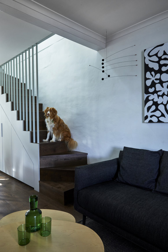 A small lounge room, with stairs leading to the second-storey extension, greets visitors as they enter the home. The artwork is by Brenda Kowalczewski. 