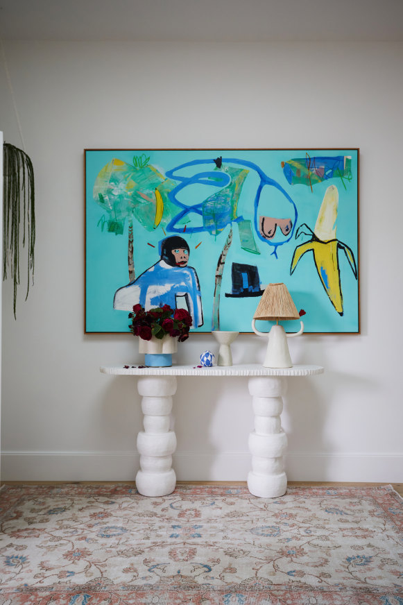 In the entry hall, a vibrant painting by Stanislas Piechaczek hangs above a console table by Gesso House.  The lamp is by Spanish ceramic sculptor Marta Bonilla and the rug is from Cadrys.