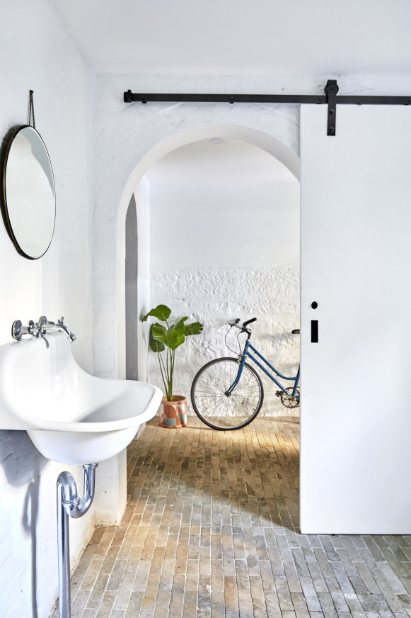 Removing the original kitchen cabinets revealed a second arched doorway to this bathroom/laundry. Rustic handmade tiles and white walls are used to create a Mediterranean feel.