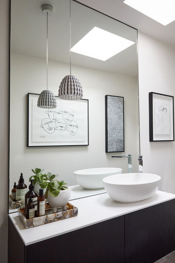 “I wanted a black and white themed gallery wall in the powder room to complement the cabinets and the Filigrana Beehive pendant light,” says Newton.
