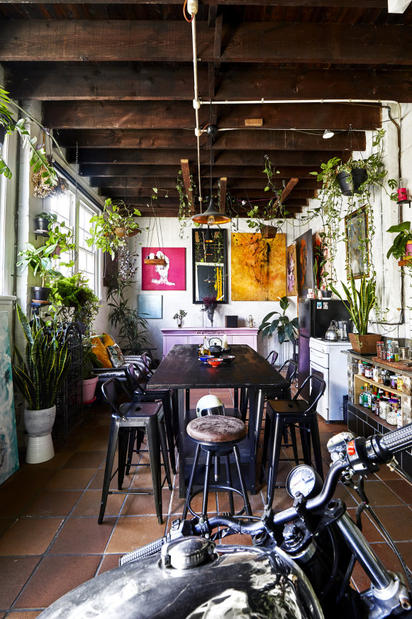 The dining room, with its “industrial vibe”, is a great place for people to gather. The table is a modified IKEA shelving unit. Paintings by Andrew Nakhla. 