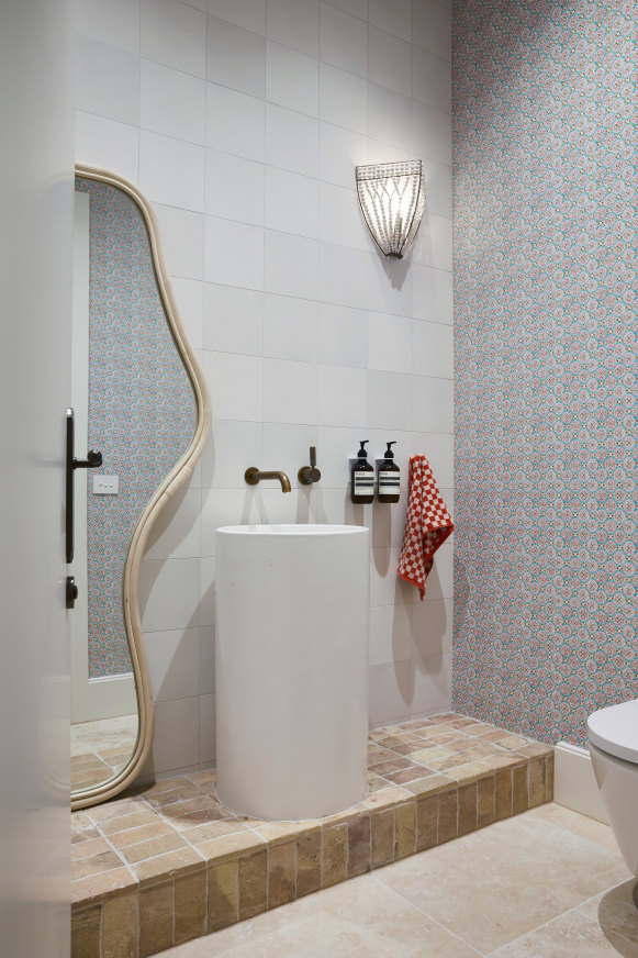 “In the powder room, we used Gather Co terracotta tiles and travertine floor 
tiles from Tiles of Ezra,” says Kerri. The “Flora” wallpaper is by Anna Spiro.