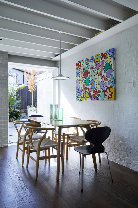 “We removed the ceiling to expose the rafters, creating textural details and more height,” says Dean Williams of the dining area. Artwork by Brenda Kowalczewski. 