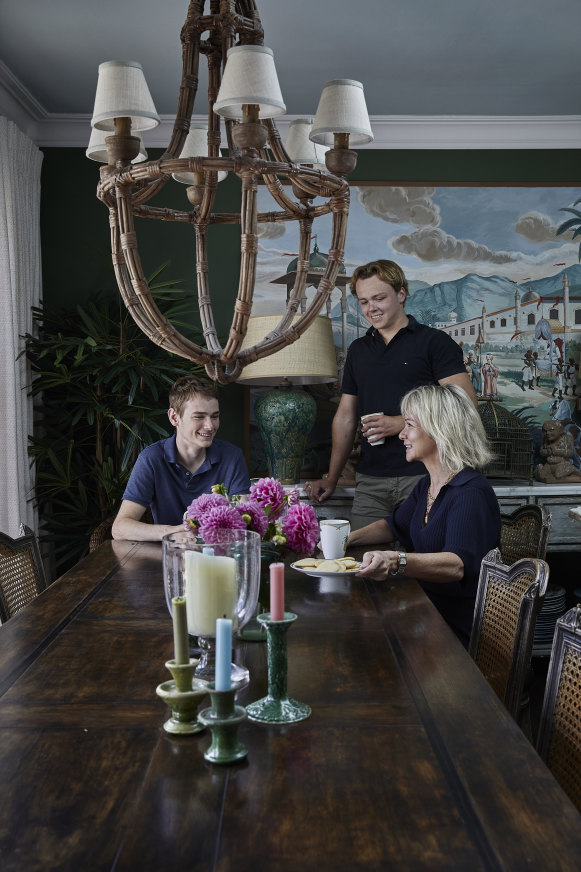 Jane Baker and sons Jack (seated) and Sam enjoy a morning coffee at the vintage French dining table. A large rattan chandelier from Isla Design hangs over the table.