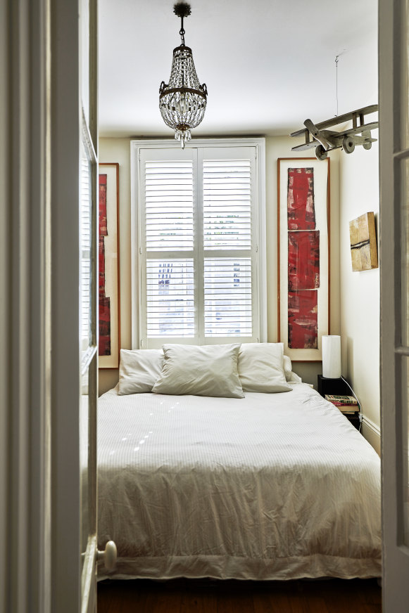 The bedroom features plantation shutters and is separated from the living room by a pair of French doors. The vertical artworks are by George Raftopoulos.