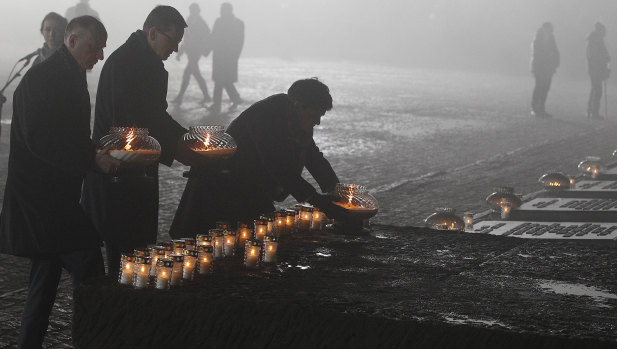 Undersecretary of State at the Chancellery of the President of Poland Wojciech Kolarski,left, Polish Prime Minister Mateusz Morawiecki and deputy Prime Minister Beata Szydlo, right, place candles at the Monument to the Victims at the former Nazi German concentration and extermination camp Auschwitz II-Birkenau, during on International Holocaust Remembrance Day in Poland on January 27.