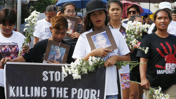 Relatives of the three youths who were killed in an alleged anti-illegal drug operation march to lay flowers and light candles at their tombs in Caloocan, north of Manila.