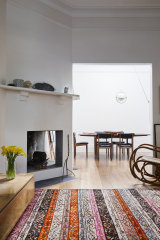 An angled open fireplace warms both the dining and formal lounge rooms. The “Multi-lite” pendant light is by Gubi, from In Good Company.