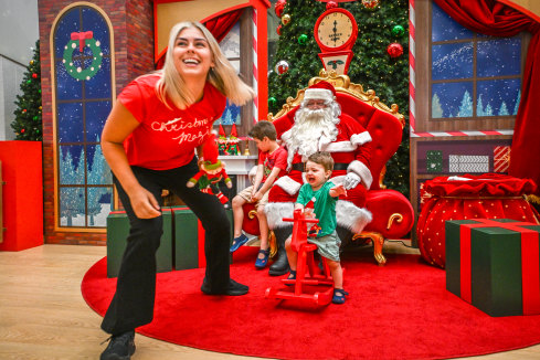 Merry work: Santa photographer Simone Morihovitis at work with Alex, 1, on rocking chair, and his brother Sam, 4.