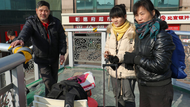 Xia Dongnan and her husband and daughter take a rest on the overpass near Beijing Railway Station.