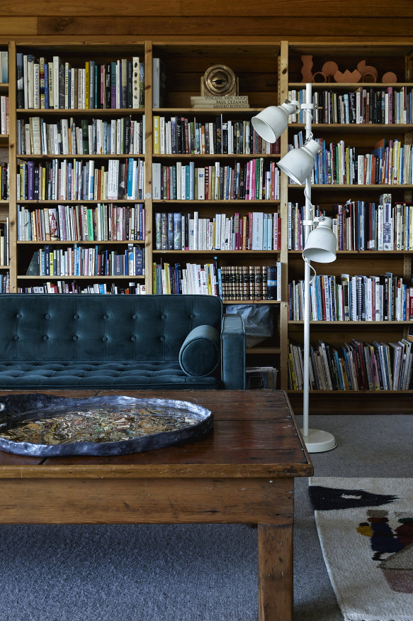 A library of art-related books lines the back of the living room. The couch and lamp are vintage and the patinated bronze platter on the table is by Mestrom.