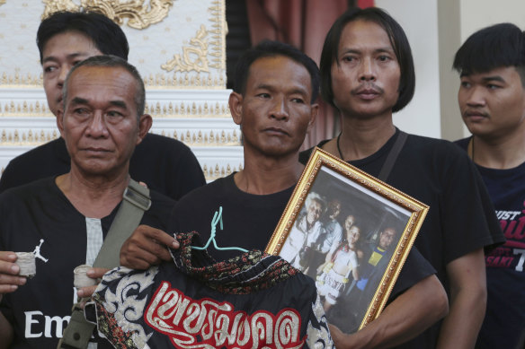 Relatives of 13-year-old Thai kickboxer Anucha Tasako hold his boxing shorts and a portrait during his funeral services in Samut Prakan province, Anucha.  He died of a brain hemorrhage two days after he was knocked out.