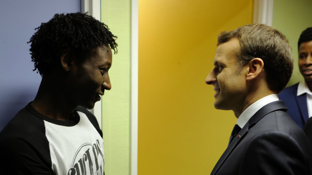 French President Emmanuel Macron shakes hands with Ahmed Adam, left, from Sudan during his visit to a migrant centre in Croisilles, northern France on Tuesday.