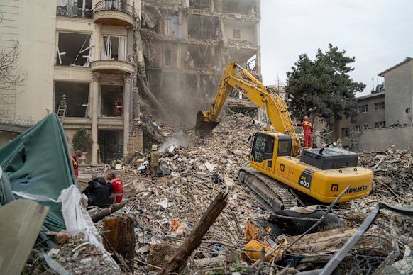 Equipes de resgate usando maquinário pesado removem destroços de um prédio residencial destruído no norte de Teerã, no Irã.