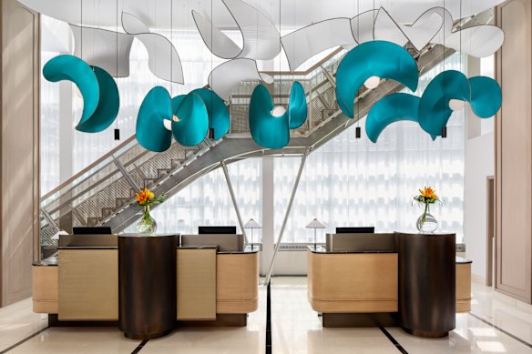 Turquoise and white sculptural light fixtures are suspended over the check-in desks.
