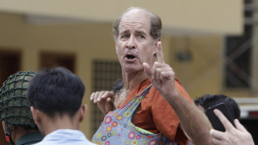 Australian filmmaker James Ricketson gestures as he is escorted by prison guards at the Cambodian Supreme Court in Phnom Penh, Cambodia, on January 17.