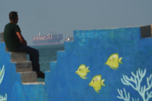 A Cargo boat navigates the sea behind a mural depicting fishes at the shoreline on Qeshm Island, Iran in the Strait of Hormuz.