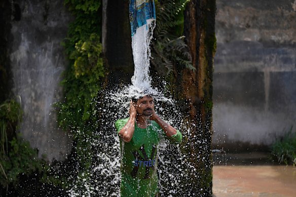 A man bathes from a roadside water tap to cool himself on a hot summer day on the outskirts of Jammu, India.