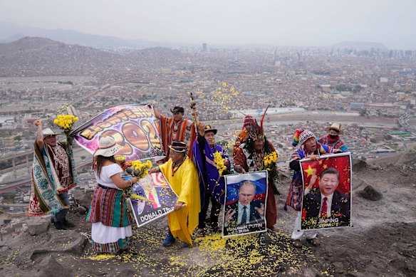 Shamans hold photos of US President-elect Donald Trump, left, Russia’s President Vladimir Putin, center, and China’s President Xi Jinping, during a year-end ritual to make predictions for the next year on the top of San Cristobal hill in Lima.