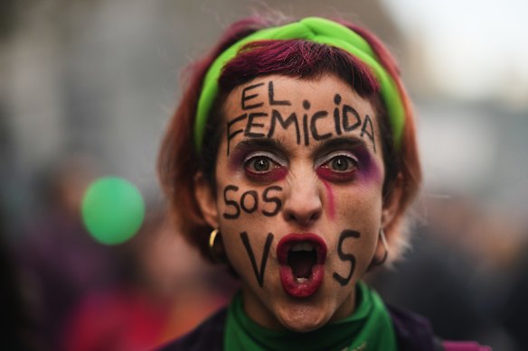 A demonstrator poses for a photo with her face painted in Spanish, "The femicide-committer is you" during a march marking the anniversary of the "Ni Una Menos" (Not One Fewer) women's movement in Buenos Aires, Argentina.