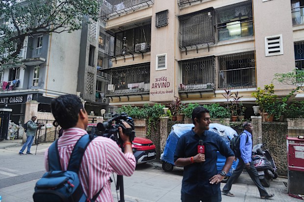 News media personnel stand outside the building where relatives of Smit Machchhar, an Indian pilot for Flydubai, previously lived in Mumbai, India