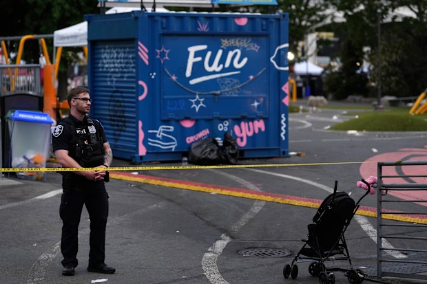 A police officer stands at a closed off area after a shooting at Seattle Center during the Bite of Seattle food festival.