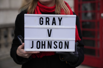 An anti-Boris Johnson protester outside the Houses of Parliament holds a placard referencing the Sue Gray inquiry.