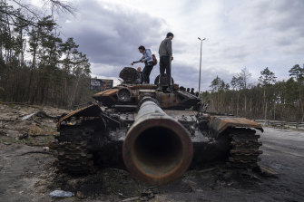 Residents stand on a Russian tank in the outskirts of Kyiv on Monday.