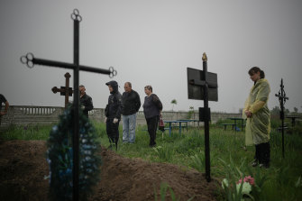 A Kuzova village resident (centre) looks on as police exhume the bodies of his mother, brother and son to investigate alleged war crimes by Russian forces during the invasion of Ukraine.