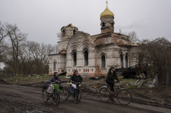 Residents pass a damaged Orthodox church, in Lukashivka, in northern Ukraine on Friday. Residents say Russian soldiers used it for storing ammunition and Ukrainian forces shelled the building to make the Russians leave.