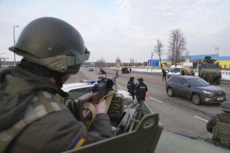 A Ukrainian National guard soldier, left, holds his weapon ready as he guards the mobile checkpoint with the Ukrainian Security Service agents and police officers in Kharkiv, Ukraine.