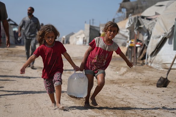 Displaced Palestinian girls carry water from a distribution point in Gaza.