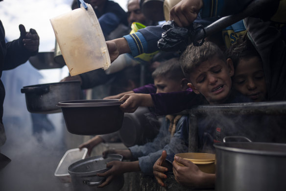 Palestinians line up for food in Rafah, Gaza Strip. Some Gazans attempting to flee, including to Australia, as international aid agencies say the territory is suffering from shortages of food, medicine and basic supplies.