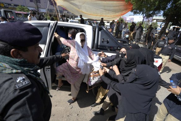 Female police officers detain a female supporter of Imran Khan protesting his arrest in Karachi.