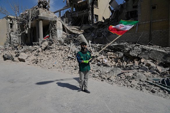 Un ragazzo sventola una bandiera iraniana davanti a una struttura di polizia colpita mercoledì durante la campagna militare israelo-americana a Teheran, in Iran.