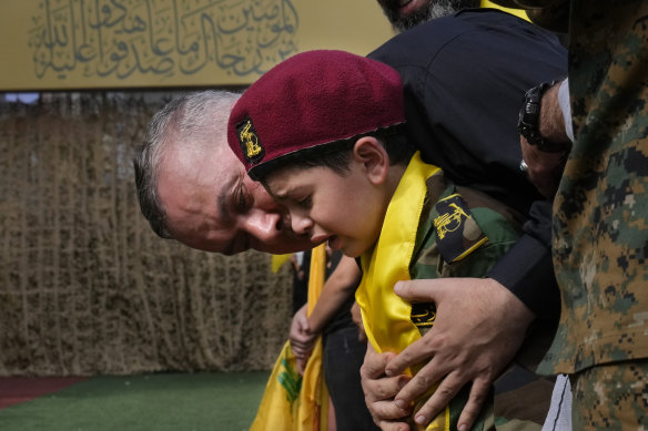 A man comforts a boy crying during the funeral procession of Hezbollah members in Beirut.