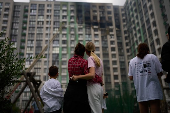Local people look on as firefighters deal with the aftermath of a Russia drone strike on a residential building in Kyiv.