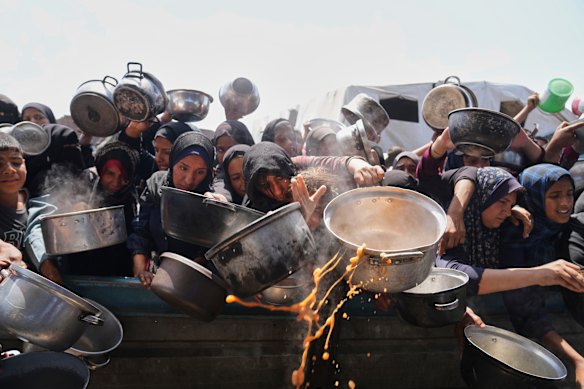 Palestinians struggle to get donated food at a community kitchen in Khan Younis, Gaza Strip.