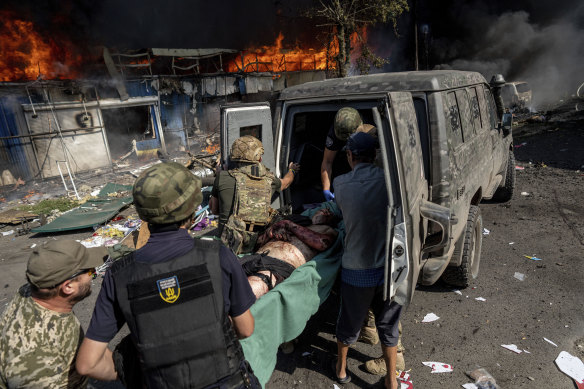 Paramedics carry an injured man into an ambulance after a Russian rocket attack on a food market in the city centre of Kostiantynivka, Ukraine.