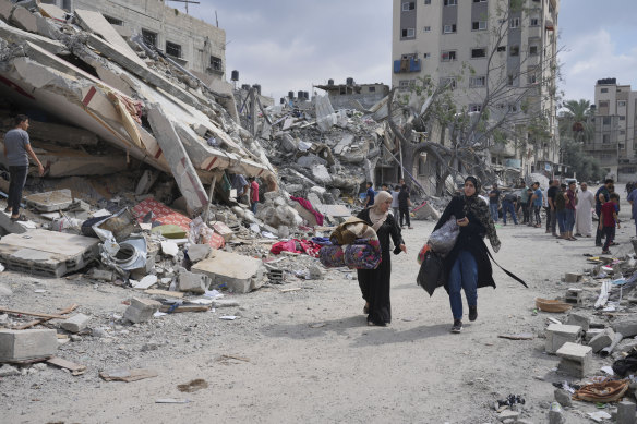 Palestinian women walk by buildings destroyed in Israeli airstrikes in Nuseirat camp in the central Gaza Strip.